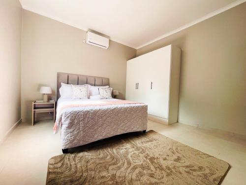 a bedroom with a large bed and a rug at The Exec Place Maun in Maun