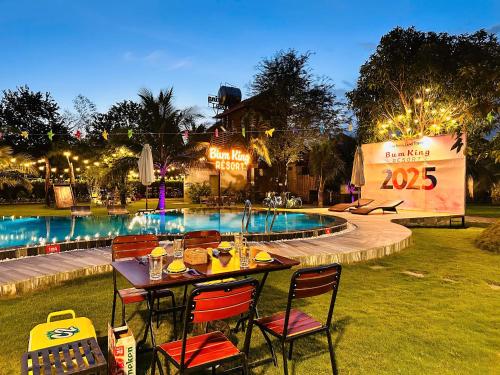 a table and chairs next to a swimming pool at night at Bum King Resort Hồ Tràm in Xuyên Mộc