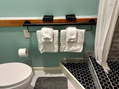 a bathroom with a toilet and towels on a shelf at Quietside Studio - Fire Pit - Near Acadia in Southwest Harbor