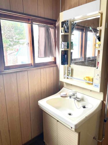 a bathroom with a sink and a mirror at Nomad Gala Otaru in Otaru