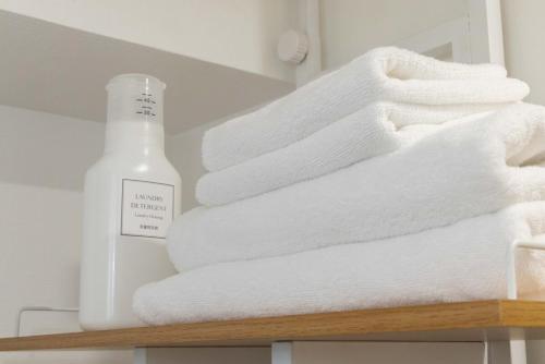 a stack of towels on a shelf with a bottle of soap at アンドステイ屋形町704 in Kyoto