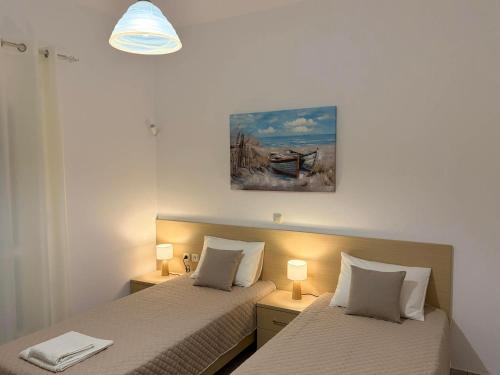 two beds in a small room with two lamps at Bernie House in Mélanes