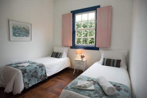 two beds in a small room with a window at Pousada da Bia in Tiradentes