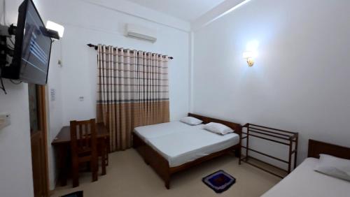 a small room with two beds and a flat screen tv at Winter Palace Lakeside in Embilipitiya