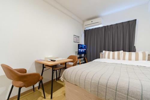 a bedroom with a bed and a table and chairs at アンドステイ屋形町507 in Kyoto