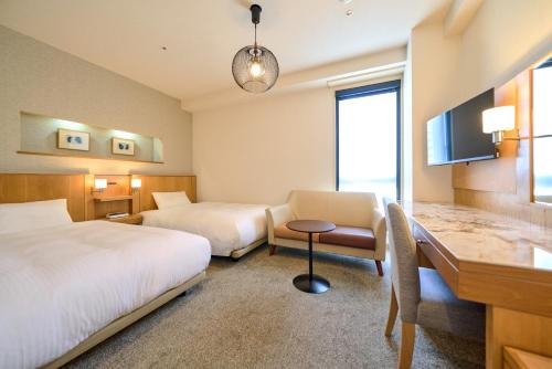 a hotel room with two beds and a desk at Hotel Global View Urawa in Saitama