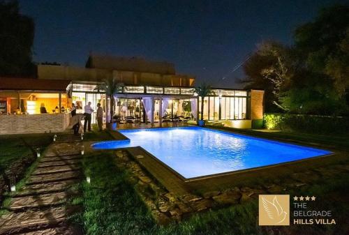 a large blue swimming pool in front of a building at The Belgrade Hills Rooms and Suites in Belgrade