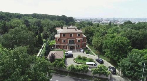 a large house with cars parked in a parking lot at The Belgrade Hills Rooms and Suites in Belgrade
