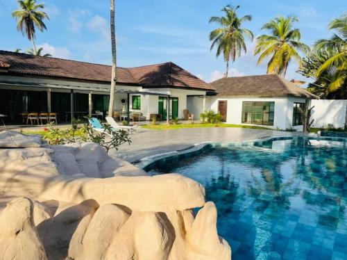 a swimming pool in front of a house with palm trees at villa zoum in Assinie
