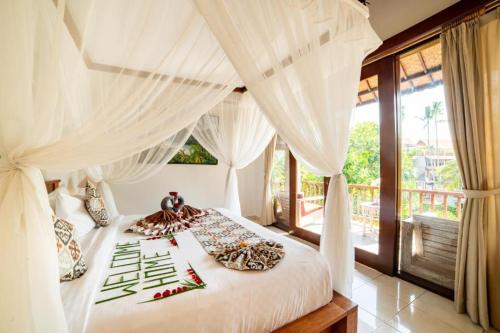 a bedroom with a white canopy bed with red peppers at Akamana Villa Ubud in Ubud