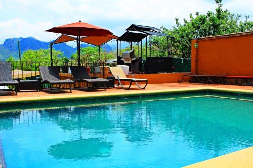 a swimming pool with chairs and umbrellas on a patio at Wellness Pet Friendly El Secreto in Tepoztlán