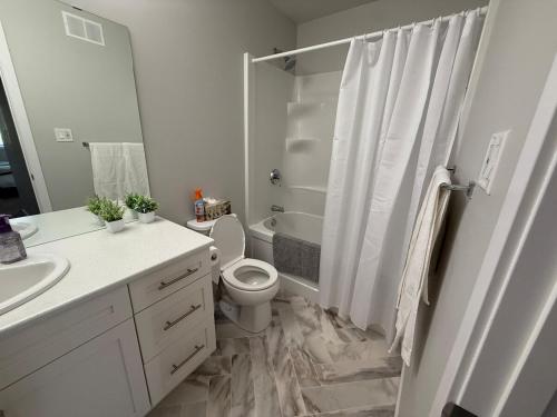 a white bathroom with a toilet and a shower at Home Away from Home in Brandon