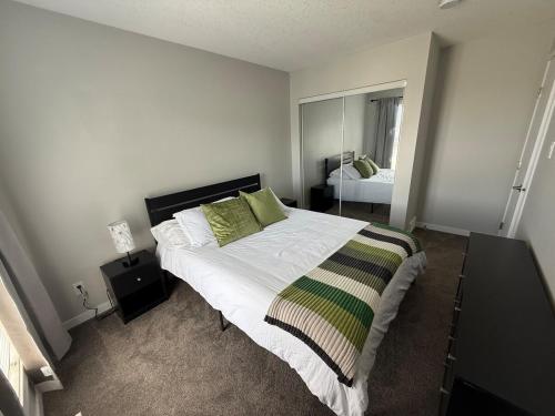 a bedroom with a large white bed with green pillows at Home Away from Home in Brandon