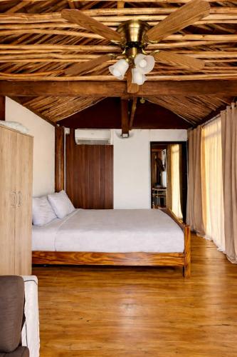 a bedroom with a bed with a ceiling fan at Thani's Little Cabin Rental - Native Room in Caibiran