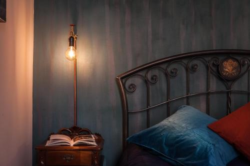 a bed with a lamp and a book on a night stand at Argilla Apartment in Rome