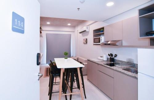 a kitchen with white cabinets and a white table and chairs at Comfy Apt w Pool & Coworking in Fernando de la Mora