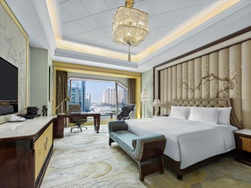 a hotel room with a bed and a desk and a television at Wanda Reign Wuhan in Wuhan