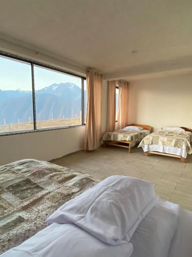 a bedroom with two beds and a large window at Casa Artesana Maras URU CUZ PE in Maras