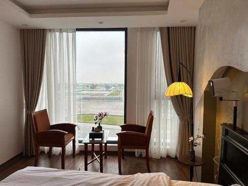 a bedroom with a table and chairs and a large window at Hotel 19 in Mỹ Lộc