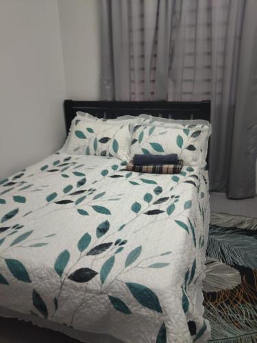 a bed with a green and white blanket and pillows at SHA HOMESTAY Budget in Tampin