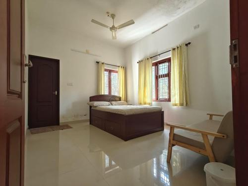 a bedroom with a bed and a chair in it at Pratheeksha Homestay in Kannur
