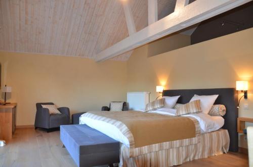 a bedroom with a large bed and a chair at B&B La Romance du Lac in Robertville