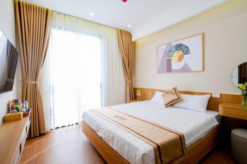 a bedroom with a bed and a large window at Amelia Sầm Sơn Boutique Holtel in Sầm Sơn
