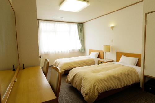 a hotel room with two beds and a window at Villa Inawashiro in Inawashiro