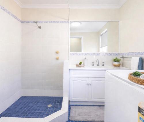 a white bathroom with a shower and a sink at Blue Waters - Beachfront and River View - Sleeps 6 -Central Kalbarri in Kalbarri