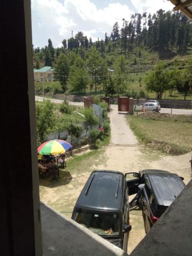 two cars parked on a dirt road with an umbrella at Bhaderwah Valley Resort in Bhadarwāh