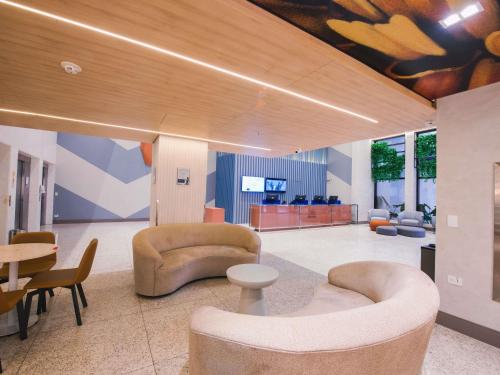 a lobby with couches and chairs and a table at ibis Curitiba Shopping in Curitiba