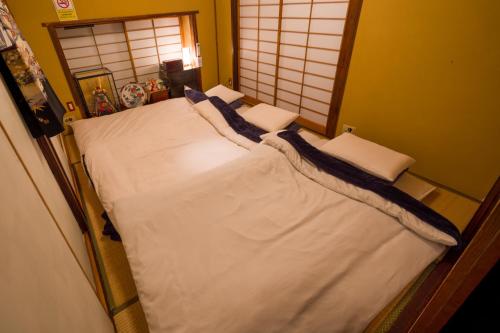 a bedroom with a bed with white sheets and pillows at Spacious Traditional Japanese House with Modern Amenities near Shibuya for Families and Groups up to 8 Guests in Tokyo