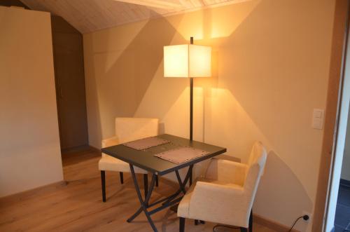 a table with chairs and a lamp in a room at B&B La Romance du Lac in Robertville