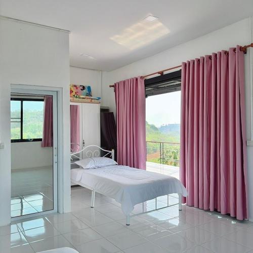 a bedroom with a bed and a window with pink curtains at Phu Man Mhok Khao Yai in Ban Nong Takhain