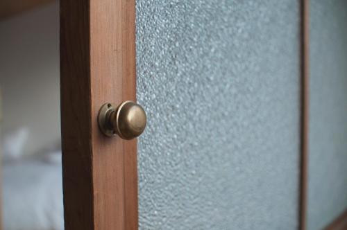 a close up of a wooden door with a glass window at Hostel Saruya in Fujiyoshida