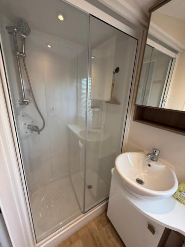 a white bathroom with a shower and a sink at Chalet Vida in Petten