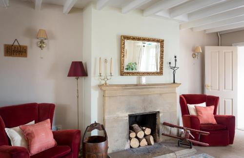 a living room with two red chairs and a fireplace at Lowerfield Farm in Broadway