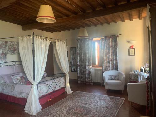 a bedroom with a canopy bed and a chair at La Canonica Di San Michele in Monteriggioni