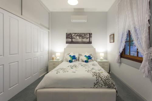 a white bedroom with a large bed with blue pillows at Rawson's Retreat - Five Bedroom Home - Walk CBD - Includes Breakfast in Tamworth
