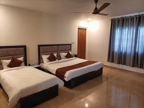 a bedroom with two beds and a ceiling fan at Hotel Grand Shiva in Gupta Kāshi