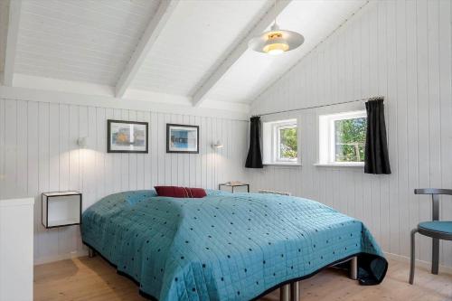 a bedroom with a bed with a blue comforter and two windows at 30305-Ulfborg-Bellisvej-504 in Ulfborg