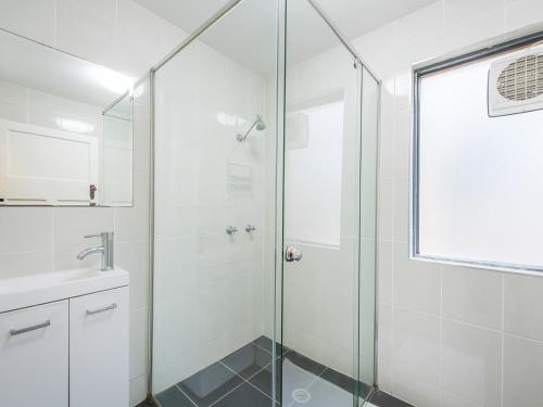 y baño con ducha acristalada y lavamanos. en Kookaburra Inn, en Brisbane