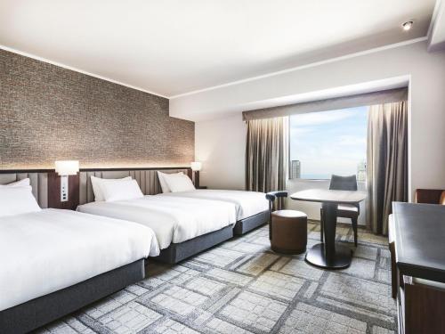 a hotel room with two beds and a desk at Hotel Hanshin Osaka in Osaka