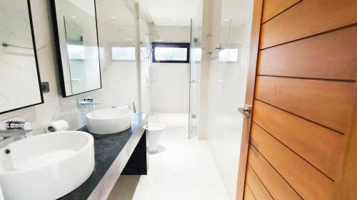 a white bathroom with two sinks and a mirror at Villa Lumina, Koh Samui in Chaweng Noi Beach