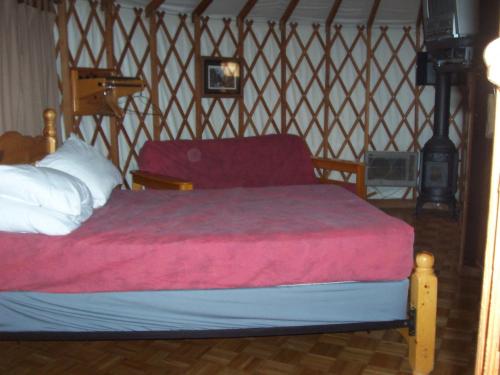 a bed with a red blanket and a chair in a room at Lake of the Springs Camping Resort Yurt 6 in Oregon House