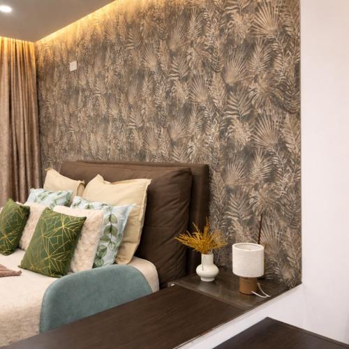 a bedroom with a couch and a wall with a wallpaper at Moonlit Terrace Escape in St. Paul's Bay