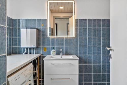 a blue tiled kitchen with a sink and a mirror at LF10243-Thyholm-Krumborgvej-3 in Hvidbjerg