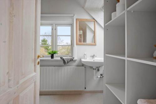 a white bathroom with a sink and a window at FY410-Faaborg-Mosetoften-10-B in Diernæs