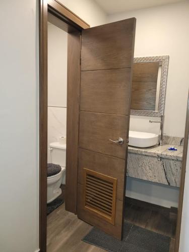 a bathroom with a toilet and a wooden door at Departamento Ejecutivo Rigo Tovar in Matamoros