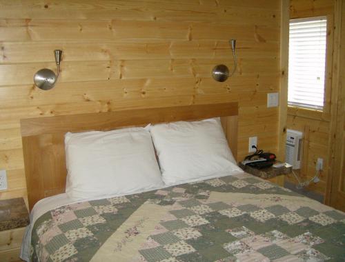 ein Schlafzimmer mit einem Bett mit einer Holzwand in der Unterkunft Lake Minden Camping Resort Cottage 2 in Nicolaus